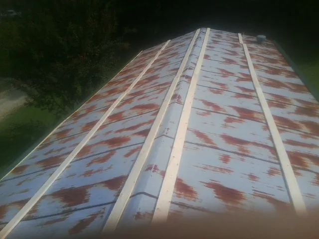 Rusted metal roof panels with new wood purlins before replacement — Storm Damage Roof Repair in Frankewing by Roofing Brothers