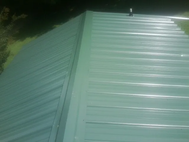 New green metal panels meeting at the ridge of a roof — Flat Roof Repair work by our crew in Frankewing