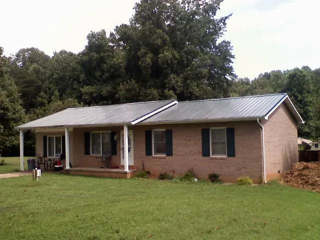 Gray metal roof on a brick ranch house with a side carport in Frankewing