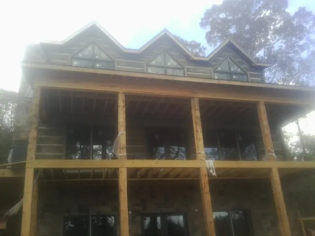 Dormers and porch framing on a large log home under construction — Roof Coating work by our crew in Frankewing