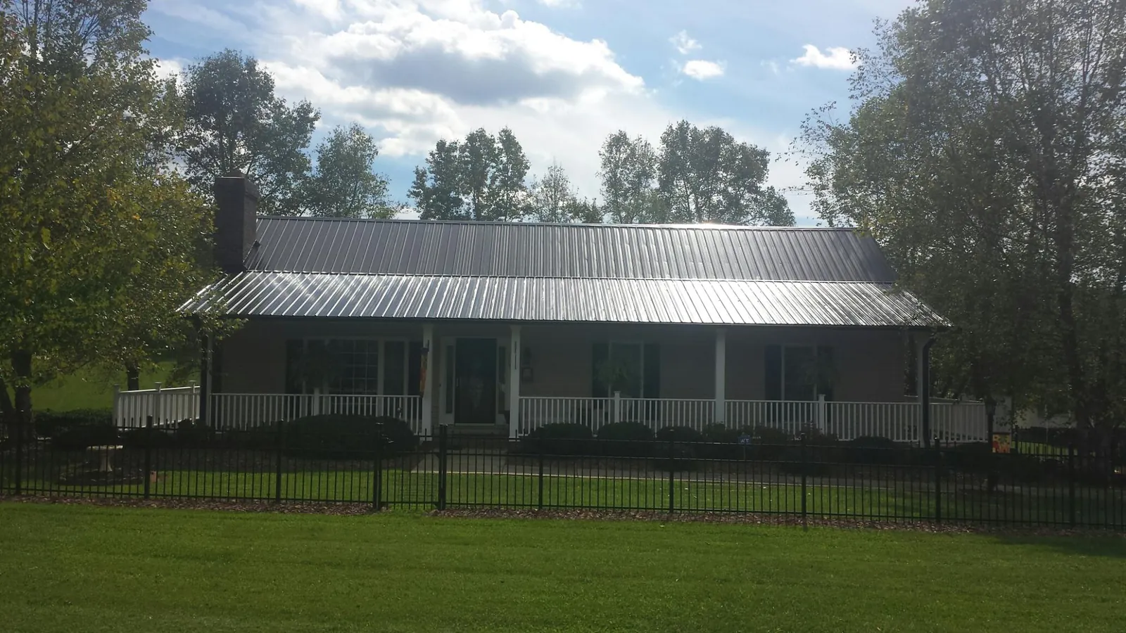 Gray metal roof on a brick ranch with a full width front porch — Gutter Guard Installation work by our crew in Frankewing