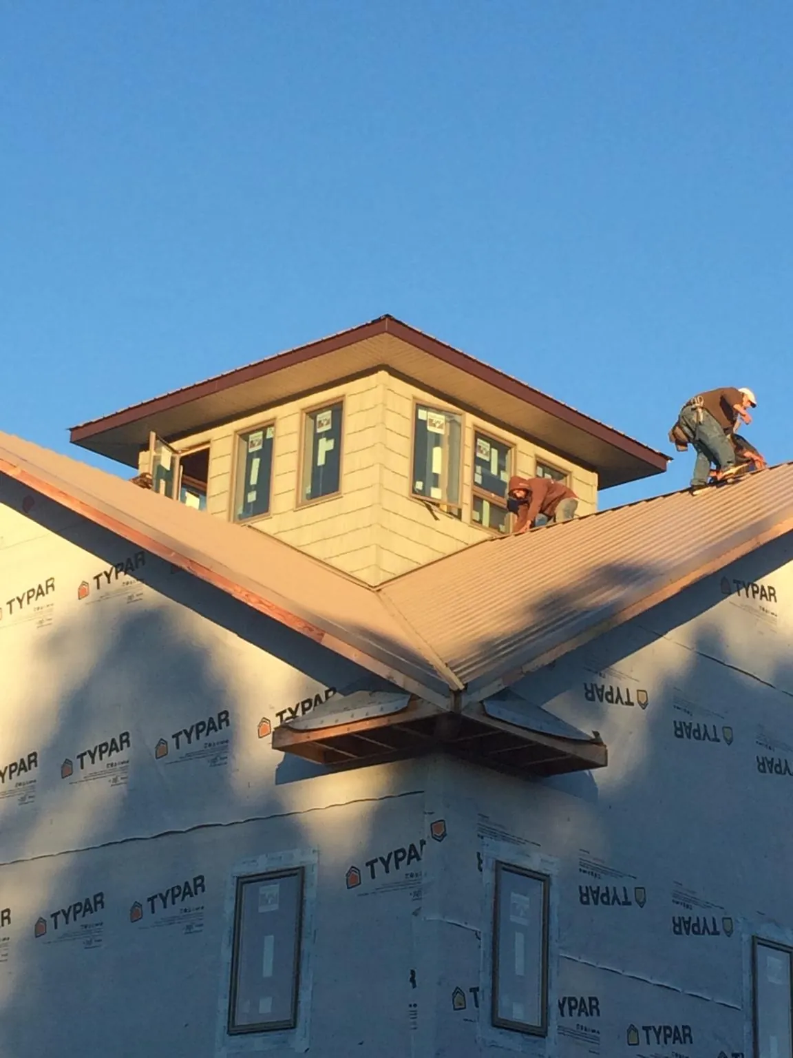 Roofers working around a rooftop cupola on a new metal roof at sunset — Roof Waterproofing in Frankewing by Roofing Brothers
